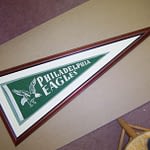 A green Philadelphia Eagles pennant flag inside a custom wooden picture frame