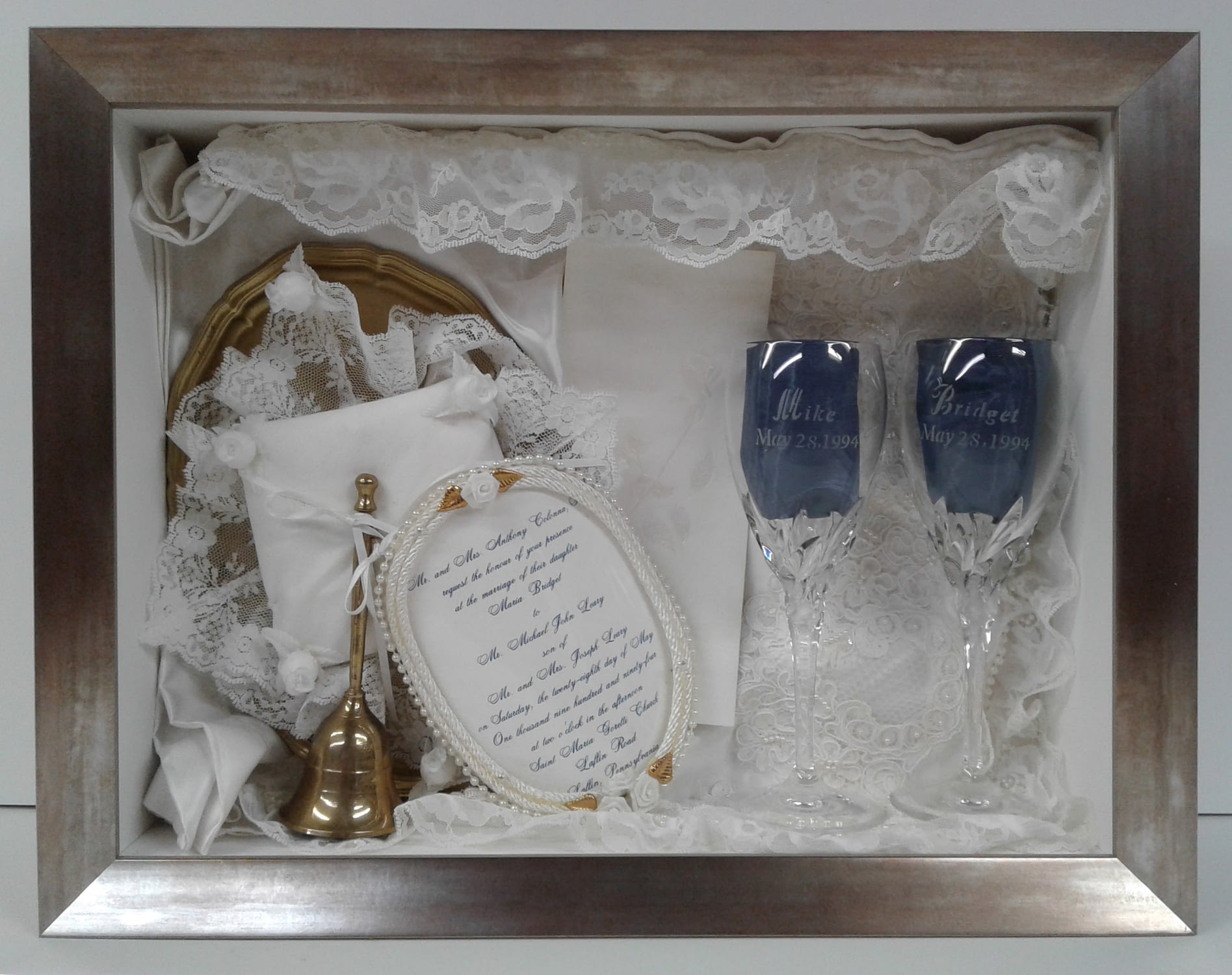 Wedding day memorabilia in a glass box with a wooden frame