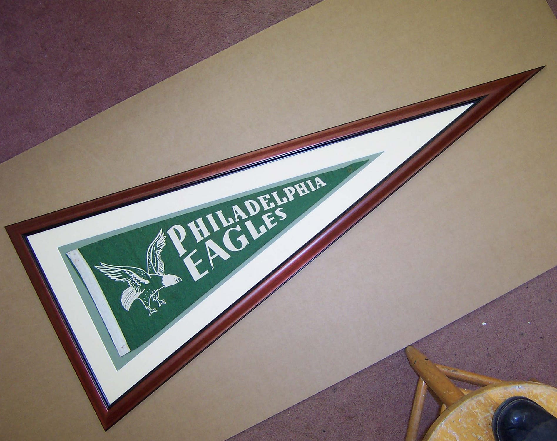 A green Philadelphia Eagles pennant flag inside a custom wooden picture frame