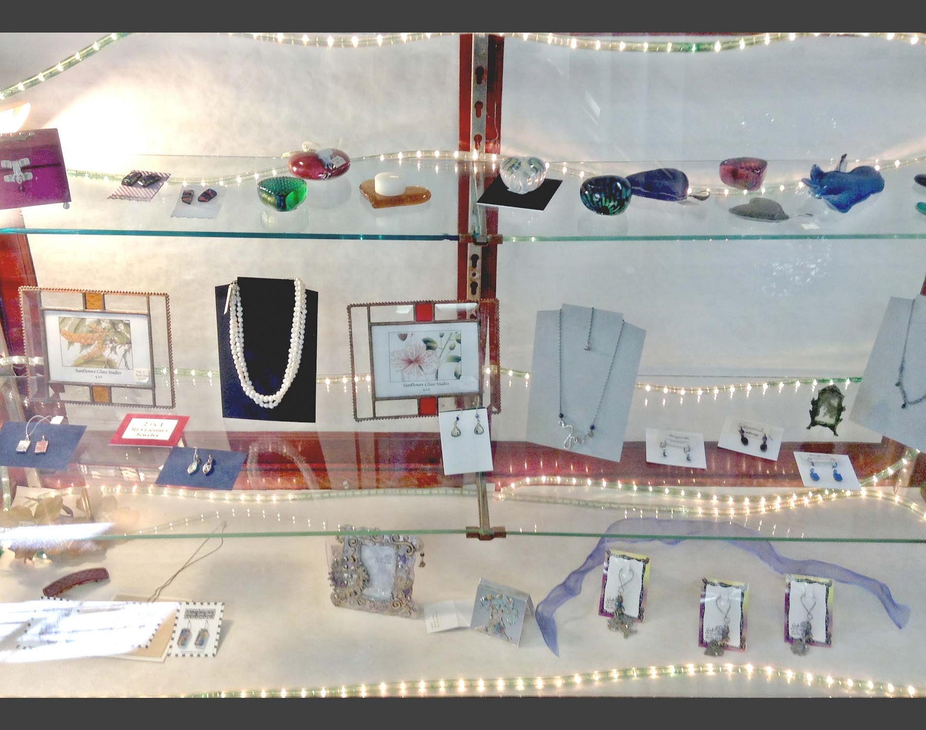 Glass shelves filled with custom jewelry, picture frames, and hand-blown glass art